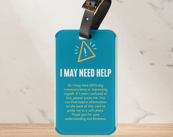 May include: Blue luggage tag with a yellow exclamation point and the text "I may need help". The tag has a black strap and a gold buckle. The text on the tag reads: "Hi, I may have difficulty communicating or expressing myself. If I seem confused or lost, please assist me. You can find helpful information on the back of this card to guide me to a safe place. Thank you for your understanding and kindness."