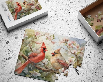 Puede incluir: Un rompecabezas con una pintura de acuarela de dos cardenales rojos posados en una rama con flores rosadas. Los cardenales están en un entorno natural con hojas verdes y un cielo azul.