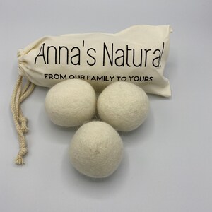 May include: Three white wool dryer balls in a white drawstring bag with the text "Anna's Natural From Our Family To Yours".