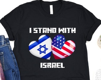 May include: Black t-shirt with the text "I Stand With Israel" in white. Two hearts are shown, one with the Israeli flag and the other with the American flag.