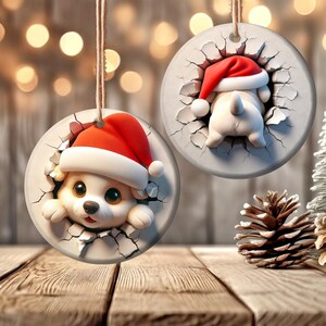 May include: Two ceramic Christmas ornaments featuring a cartoon dog wearing a Santa hat. The dog is peeking out of a cracked wall.