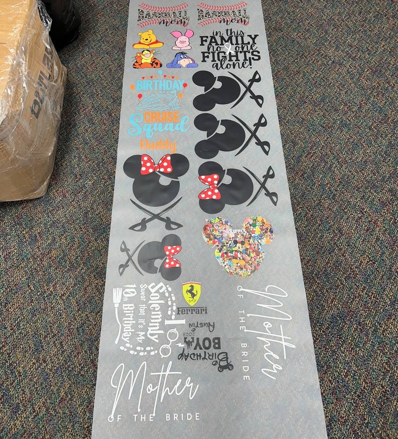 May include: A sheet of white vinyl with black and colored text and images. The text includes "Baseball Mom", "In this family no one fights alone", "Birthday Cruise Squad", "Solemnly swear that it's my 10th birthday", "Ferrari", "Austin Boy Birthday 2023", and "Mother of the Bride". The images include Mickey Mouse, Minnie Mouse, a baseball, a cruise ship, a Ferrari logo, and a birthday cake.