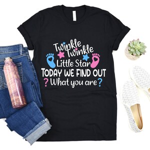 May include: Black t-shirt with the text "Twinkle Twinkle Little Star Today We Find Out ? What you are?" with a pink and blue footprint and star graphic.