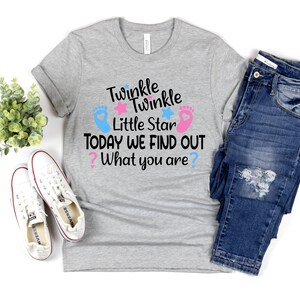 May include: A gray t-shirt with the text "Twinkle Twinkle Little Star Today We Find Out What You Are?" in black. The text is surrounded by two pink and blue footprints and stars.