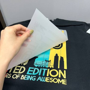 May include: A black t-shirt with a colorful graphic design featuring a cityscape and the text "Limited Edition 10 Years of Being Awesome".
