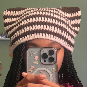 May include: A brown and pink striped crocheted hat with cat ears.