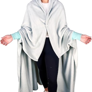 May include: A light blue wearable blanket with sleeves. The blanket is made of soft, plush fabric and has a shawl collar. The sleeves are a lighter shade of blue and have a contrasting trim.