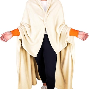 Puede incluir: Una manta de forro polar de color crema con ribetes naranjas en las mangas. La manta se lleva como una bata y tiene un cuello chal.