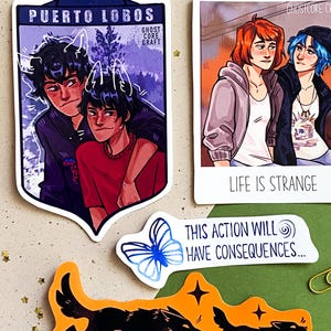 Könnte beinhalten: Eine Sammlung farbenfroher Aufkleber mit Illustrationen. Ein Aufkleber zeigt zwei Figuren mit dem Text "PUERTO LOBOS". Ein anderer zeigt zwei Frauen mit dem Text "LIFE IS STRANGE". Ein dritter Aufkleber hat einen blauen Schmetterling und den Text "THIS ACTION WILL HAVE CONSEQUENCES..." und ein vierter Aufkleber hat zwei Wölfe mit dem Text "THE WOLF BROTHERS".