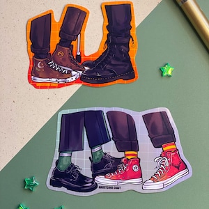 Può includere: Due fogli di adesivi con illustrazioni di gambe e calzature. Un foglio mostra sneakers alte marroni, stivali neri e stivali marroni. L'altro foglio mostra scarpe nere, sneakers alte rosse. Il testo "GHOSTCORE CRAFT" è visibile.