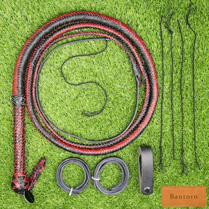 Puede incluir: Un látigo de cuero negro y rojo con un mango trenzado y un látigo largo y delgado. El látigo está enrollado sobre una superficie verde, con accesorios de cuero negro adicionales, que incluyen un lazo para el mango y varios cordones delgados. La palabra "Bantoro" está impresa en una etiqueta marrón.