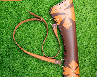 May include: A brown and tan leather quiver with a shoulder strap. The quiver has decorative stitching and brass rivets. The word "Bantoro" is printed on a small rectangular tag.