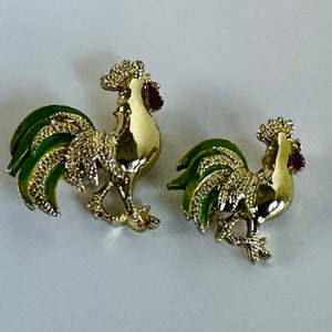 May include: Two gold-colored rooster brooches with green and red enamel accents.