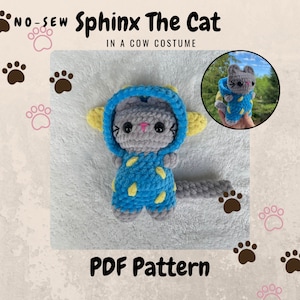 Puede incluir: Un patrón de crochet para un gato gris que lleva un disfraz de vaca azul y amarillo. El patrón se llama "Sphynx The Cat in a Cow Costume" y es un patrón PDF sin costuras.