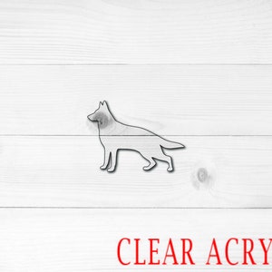 May include: A clear acrylic silhouette of a German Shepherd dog. The dog is standing in profile with its head turned to the left.