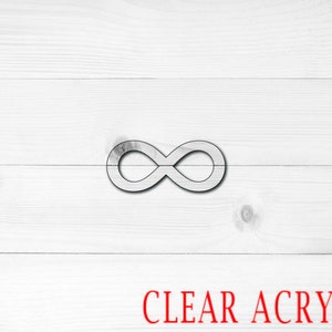 May include: A clear acrylic infinity symbol on a white wood background. The text "CLEAR ACRYLIC" is written in red below the symbol.