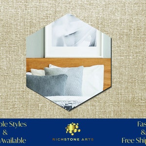May include: A hexagonal mirror with beveled edges reflects a bedroom interior with a wooden headboard, white bedding, and blue throw pillows. The mirror is set against a beige linen background. The text "RICHSTONE ARTS" is visible below the mirror.