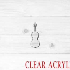 May include: A clear acrylic violin cutout on a white wood background. The text "CLEAR ACRYLIC" is printed in red below the cutout.