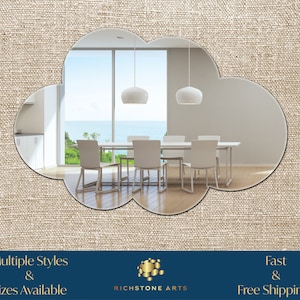 May include: A cloud-shaped mirror with a beveled edge, reflecting a modern dining room with a table and chairs. The mirror is set against a beige linen background. The text "Multiple Styles & Sizes Available" and "Fast & Free Shipping!" is displayed below the mirror.