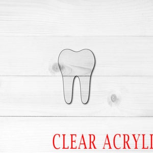 May include: A clear acrylic tooth cutout on a white wood background. The text "CLEAR ACRYLIC" is printed in red below the cutout.