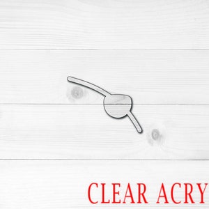 May include: A clear acrylic pirate eye patch with a black outline. The patch is on a white wood background.