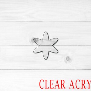May include: A clear acrylic star-shaped cutout on a white wood background. The text "CLEAR ACRYLIC" is printed in red below the star.