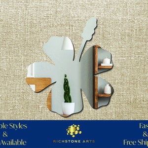 May include: A mirrored hibiscus flower wall decor with a silver finish. The flower is shown reflecting a plant in a white pot.  Multiple Styles & Sizes Available. Richstone Arts.