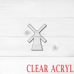 May include: A white windmill cutout made of clear acrylic. The windmill is on a white wood background with the words "CLEAR ACRYLIC" in red text below it.