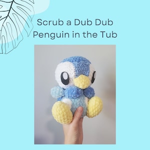 Pode incluir: Um brinquedo de pelúcia de pinguim azul e branco de crochê com detalhes amarelos. O pinguim está sendo segurado em uma mão. O texto "Scrub a Dub Dub Penguin in the Tub" está acima da imagem e "by @smolivco" está abaixo da imagem.