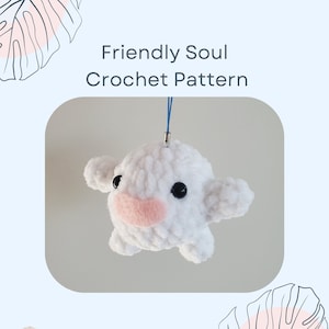 May include: White crocheted amigurumi toy with black eyes and a pink nose. The toy is shaped like a small animal with rounded ears and a small mouth. The toy is hanging from a blue string.