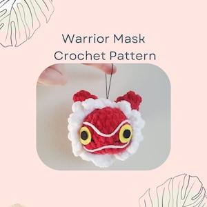 May include: Crochet pattern for a red warrior mask with white fur trim and yellow eyes. The mask is hanging from a black string.
