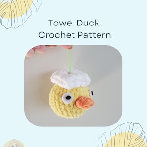 May include: A crocheted yellow duck with a white crocheted hat. The duck has orange felt for a beak and black felt for eyes. The duck is hanging from a green string.