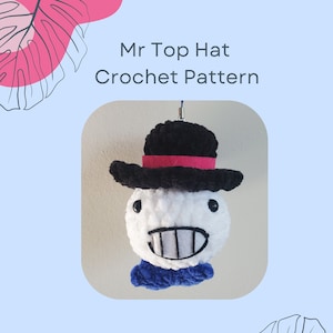 May include: Crochet pattern for a white amigurumi character with a black top hat, pink band, blue scarf, and a toothy grin. The pattern is called "Mr Top Hat".
