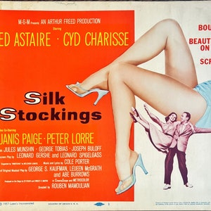 Könnte beinhalten: Ein Filmplakat für den Film "Silk Stockings" mit Fred Astaire und Cyd Charisse. Das Plakat hat einen roten Hintergrund mit dem Titel in großen weißen Buchstaben. Das Plakat zeigt auch ein Foto von Cyd Charisse in einem blauen Kleid, mit ihren Beinen in die Luft gestreckt. Das Plakat zeigt auch ein Foto von Fred Astaire und Janis Paige beim Tanzen.