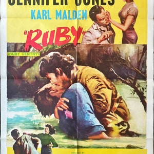 May include: Movie poster for the film "Ruby" starring Charlton Heston, Jennifer Jones, and Karl Malden. The poster features a yellow background with a red title and a scene of the actors in a romantic embrace.