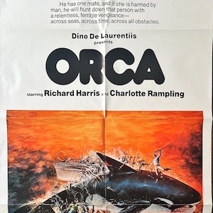 May include: A movie poster for the film "Orca" starring Richard Harris and Charlotte Rampling. The poster features a black and white image of a killer whale attacking a boat with a man on top of it. The poster is set against a background of an orange sunset.