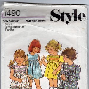 以下が含まれることがあります： さまざまなドレスを着た4人の女の子が描かれた、ヴィンテージの幼児用ドレスの縫製パターン。 パターンはサイズ2で、胸囲53cm（21インチ）です。 「Style」の文字が上部に大きな黒い文字で印刷されています。