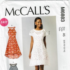 May include: McCall's M6883 sewing pattern envelope featuring three dress variations. One is a white floral eyelet dress with short sleeves, while the other two are sleeveless halter-style dresses in orange floral and black and white geometric prints.