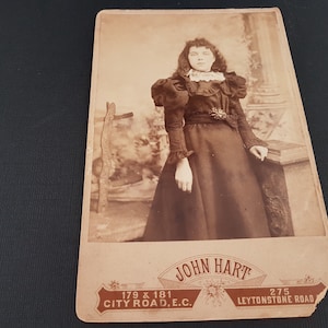 Antique mid to late victorian sepia photograph with decorative back. A young lady with ringlet hair in high victorian clothing and leg o mutton sleeves. Lower front printed with John Hart Leystone Rd London In excellent condition
Size 10.5cm x 16.5cm