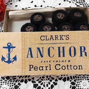 May include: A box of Clark's Anchor Fast Colour Pearl Cotton thread spools. The box is brown with a white anchor and rope design. The text "Clark's Anchor Fast Colour Pearl Cotton" is printed on the box.