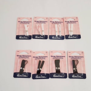 May include: Multiple packs of strap retainers for sleeveless clothing. The packaging is pink and white, with the brand name "Hemline". The retainers are available in white and black.