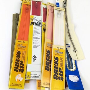 May include: Assortment of zipper packages in various colours, including orange, red, pink, white, and beige. The packages are labelled "Dress Zip" and feature the text "Aero Polyester" and "Fully Guaranteed".