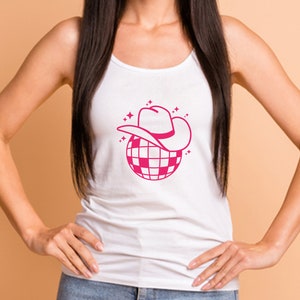 Pu&ograve; includere: Un top bianco senza maniche con un design a palla da discoteca rosa. La palla da discoteca &egrave; sormontata da un cappello da cowboy rosa.