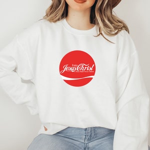 May include: White sweatshirt with a red circle logo that says "Enjoy Jesus Christ Thou Shalt Never Thirst".