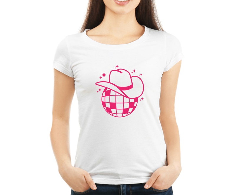 Pu&ograve; includere: Una maglietta bianca con un design a forma di palla da discoteca rosa. La palla da discoteca ha un cappello da cowboy rosa in cima.