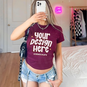 May include: A maroon cropped t-shirt with the text "your design here" in yellow and white. The shirt has a star design on the bottom and the text "AVIEMOCKUPS" in white.