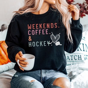 May include: Black sweatshirt with the text "Weekends. Coffee. & Hockey." in pink, red, and green with a heart and hockey puck graphic.