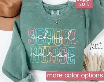 May include: Light green sweatshirt with the text "SCHOOL NURSE" in rainbow colors. The sweatshirt is super soft and has more color options.