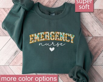May include: A dark green sweatshirt with the text "EMERGENCY nurse" in floral letters. The sweatshirt is super soft and has a white heart below the text.
