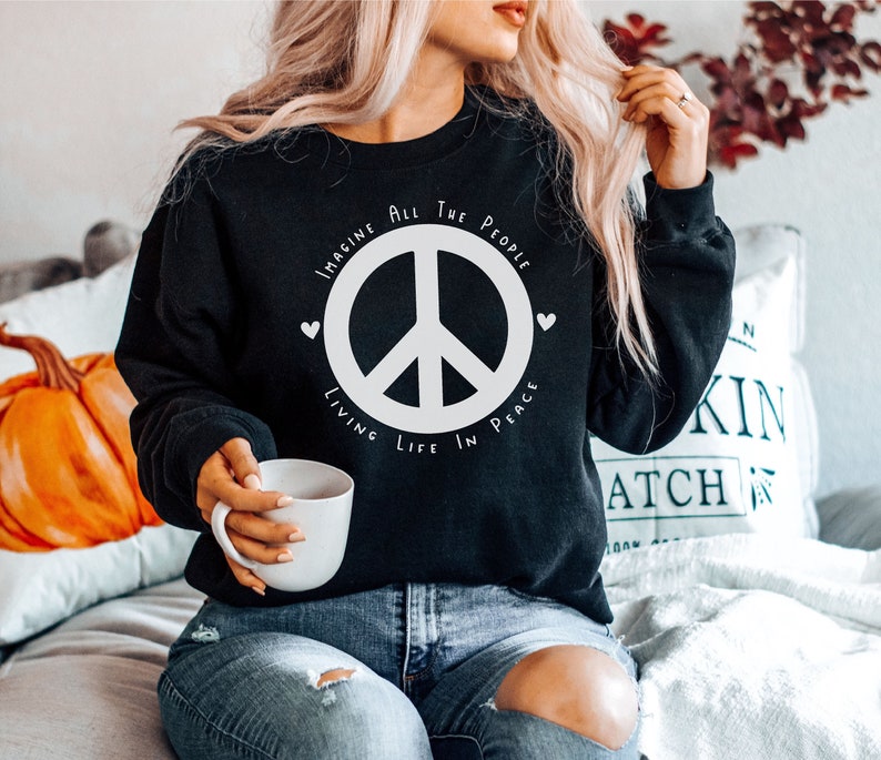 May include: A black sweatshirt with a white peace sign and the text "Imagine All The People Living Life In Peace".
